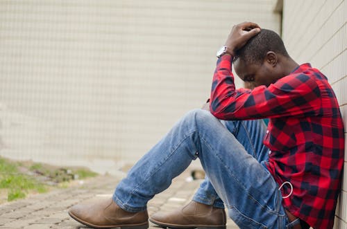 Pria Dengan Kemeja Kotak Kotak Merah Dan Biru Dan Jeans Denim Biru Duduk Di Lantai Selama