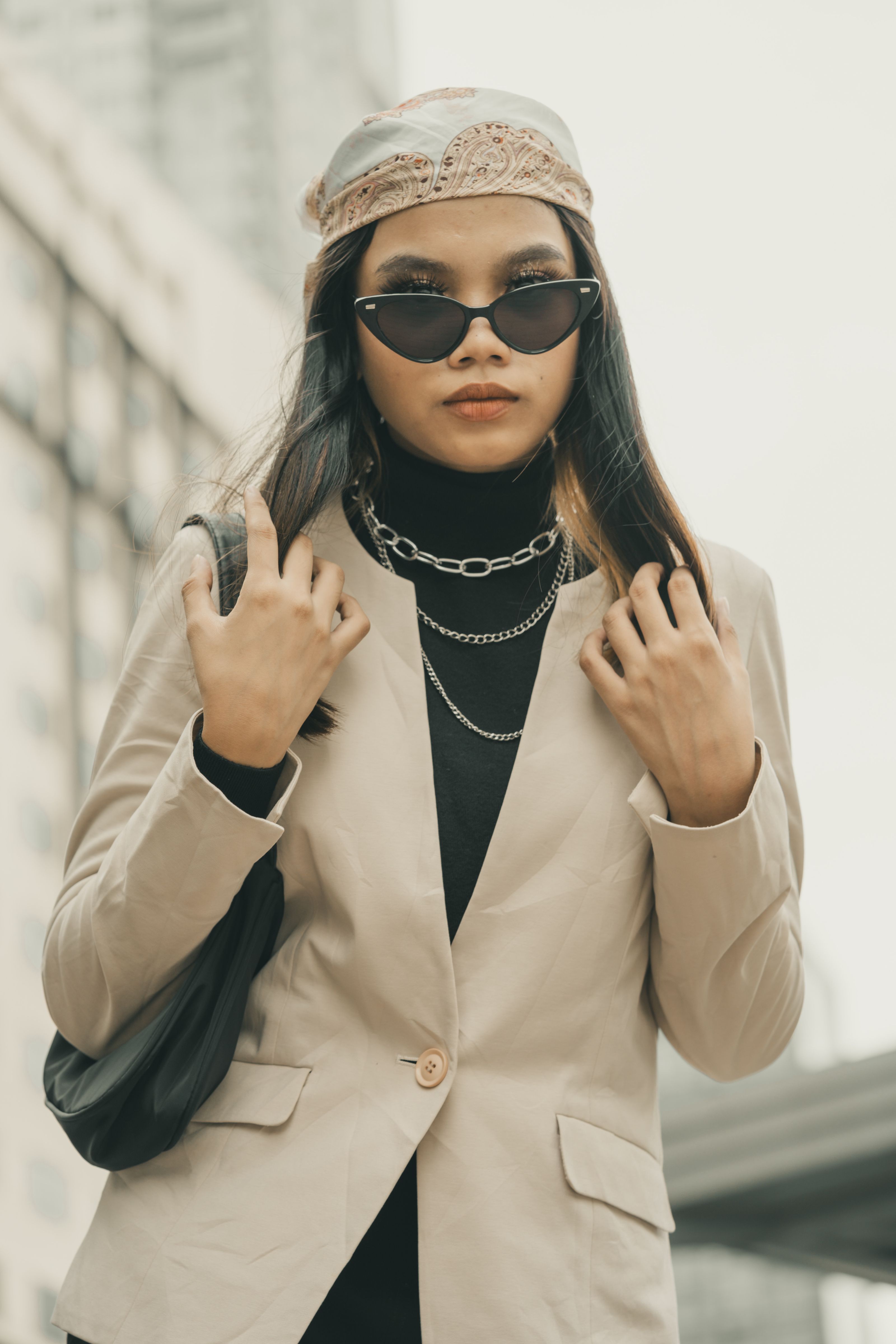Retrato de uma mulher estilosa com óculos de sol e um traje chique posando ao ar livre na cidade.