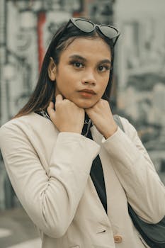 Portrait of a fashionable woman in a beige blazer and sunglasses, posing confidently outdoors.