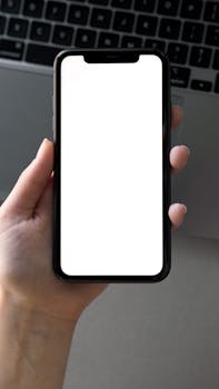 A close-up of a hand holding a smartphone with a blank screen, ideal for mockups.