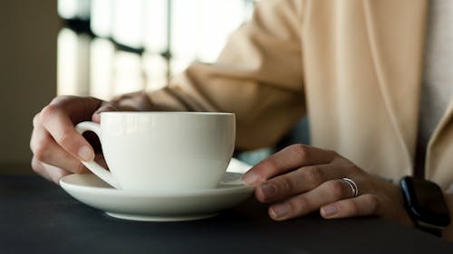 Person Holding a White Ceramic Cup
