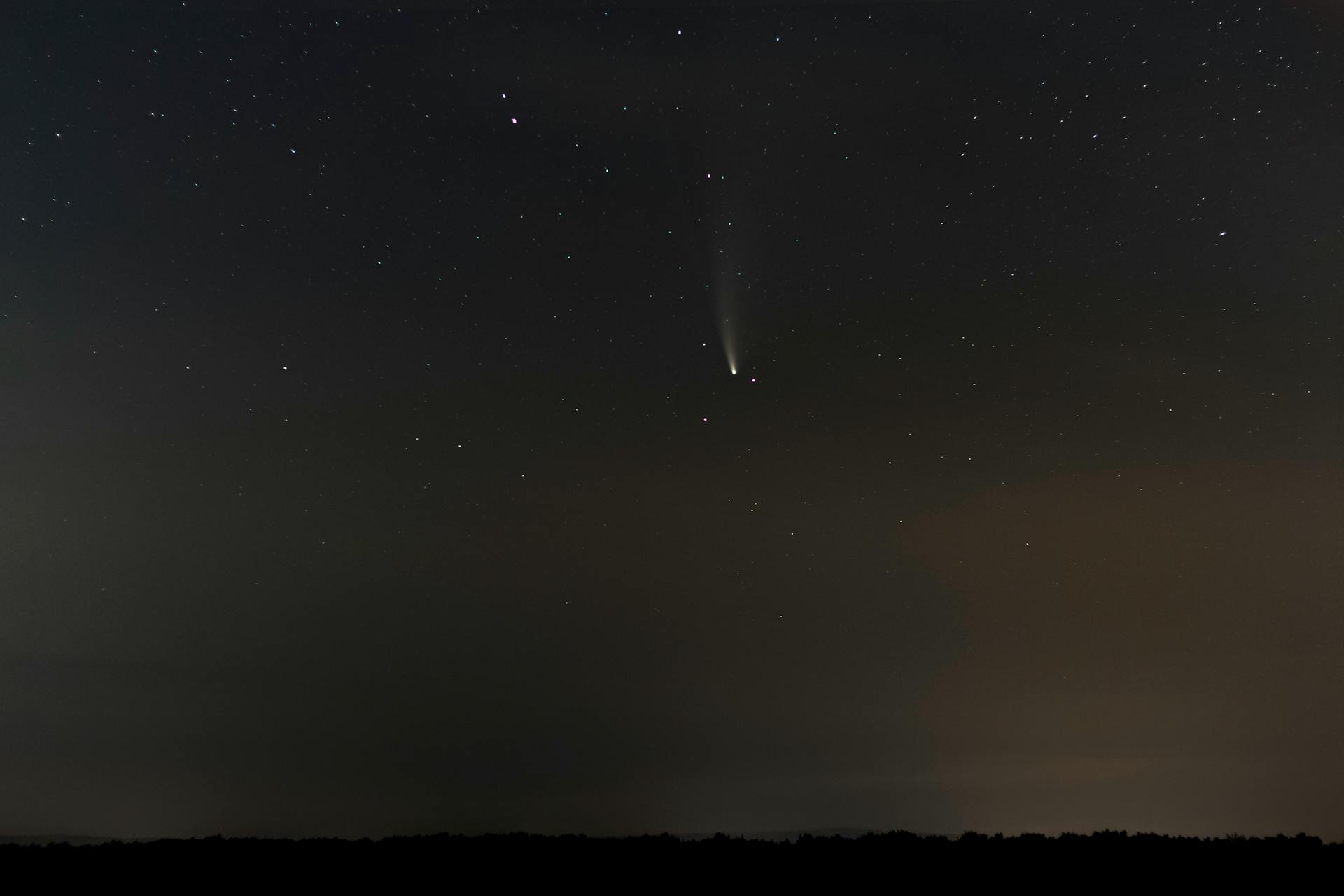 A mesmerizing view of the night sky featuring a vivid shooting star against a starry backdrop.