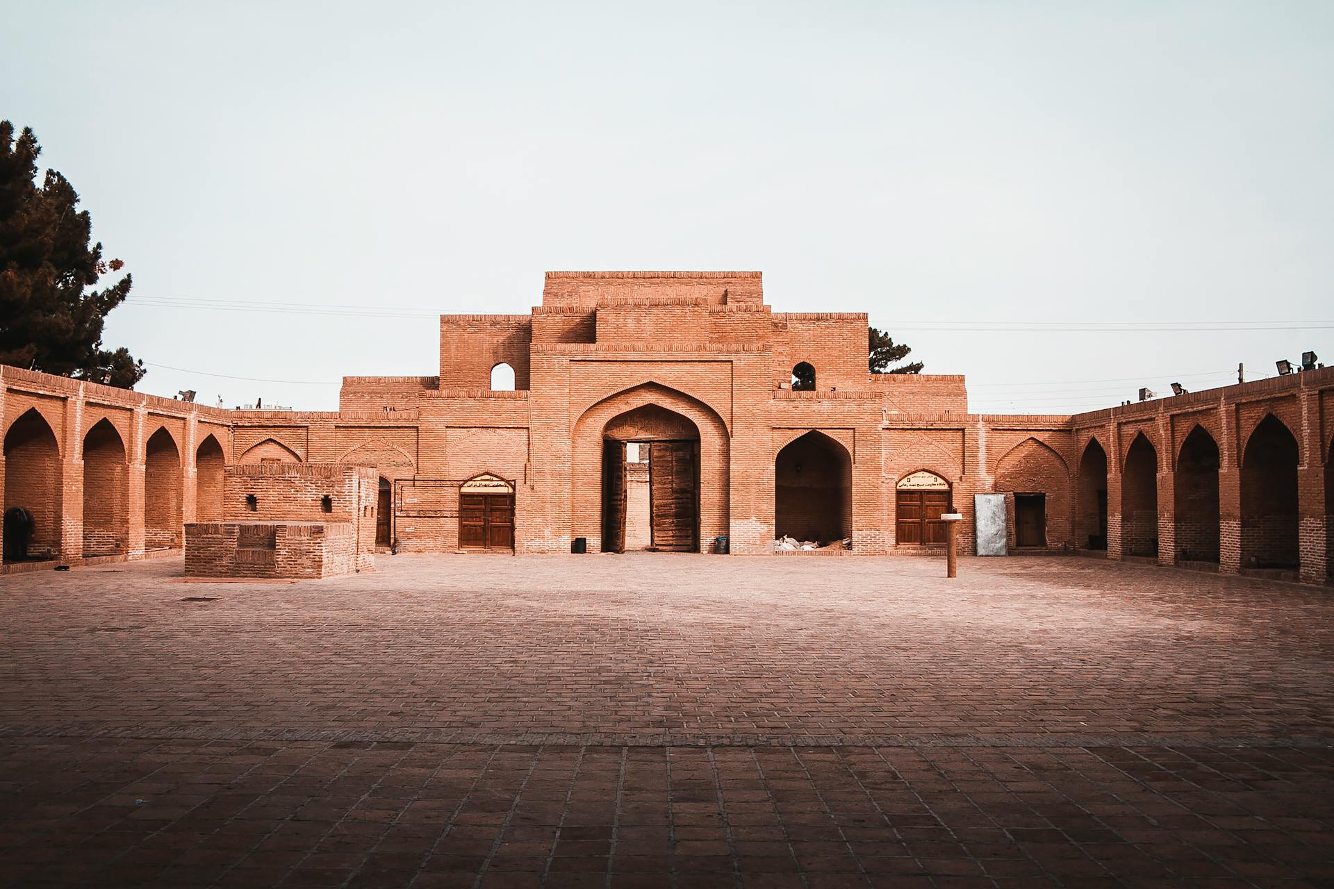 A beautifully preserved historic courtyard featuring red stone arches and building structures.