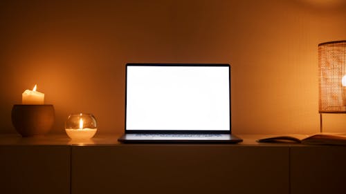 A Laptop with a Blank White Screen in a Room wit Dim Lighting