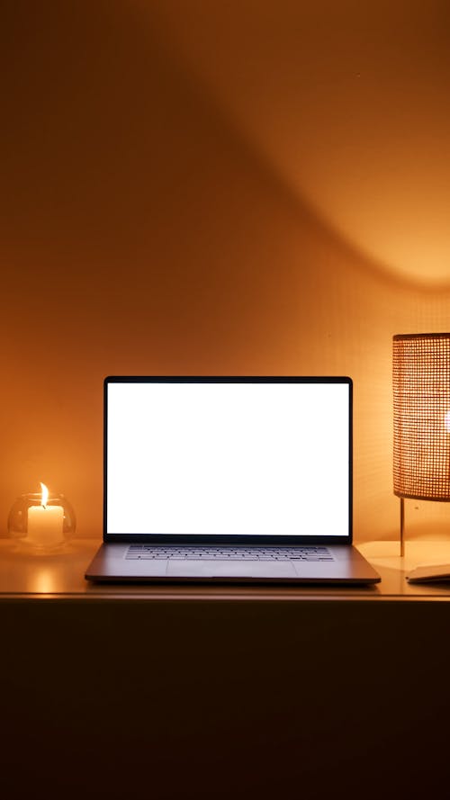 Photo of a Laptop Beside a Lit Candle