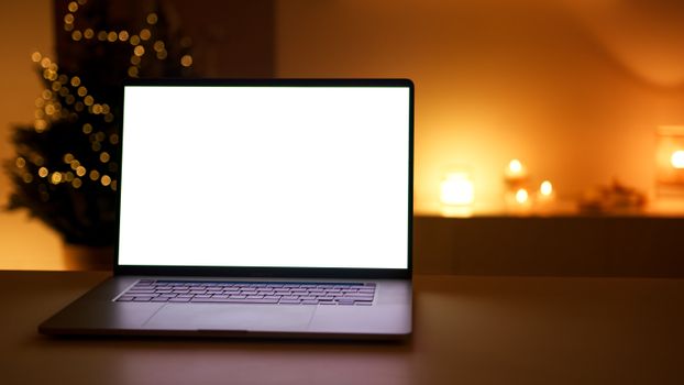 Warm candlelit desk setup featuring a laptop and Christmas lights creating a cozy atmosphere.