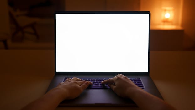 Hands typing on a laptop with a blank screen, creating a cozy and quiet workspace atmosphere indoors.