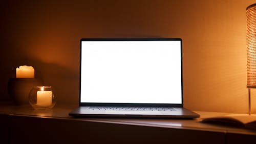 Photo of a Laptop Near a Lit Candle