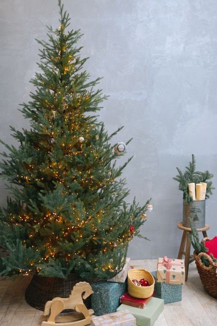 Festive Christmas tree with lights and gifts in a cozy indoor setting.
