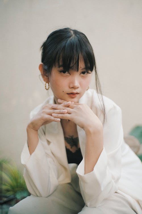 Charming ethnic lady sitting near wall on chair