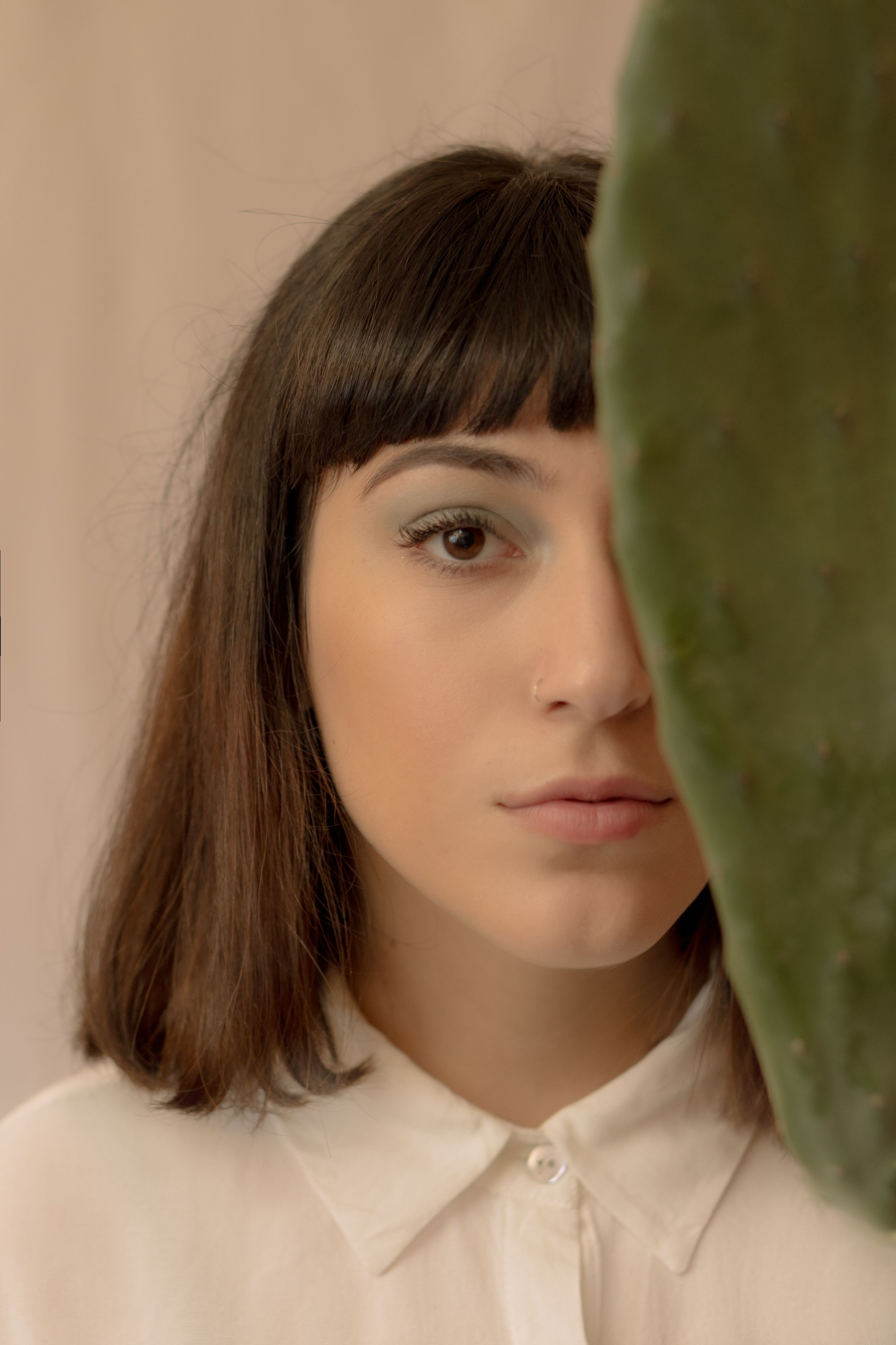 Artistic portrait of a woman partially obscured by a cactus leaf, creating a unique visual balance.