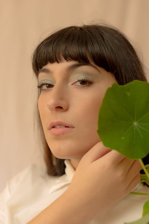 Free A Woman Holding Green Leaf Near Her Face Stock Photo