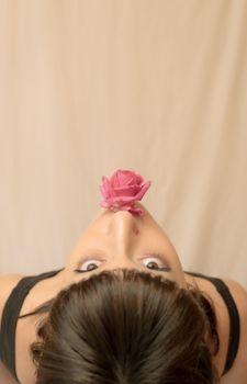 Artistic top view portrait of a woman with a pink rose held over her face.