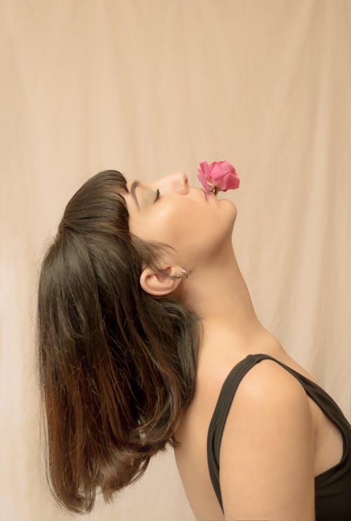 Женщина в черной майке с розовой розой на ухе