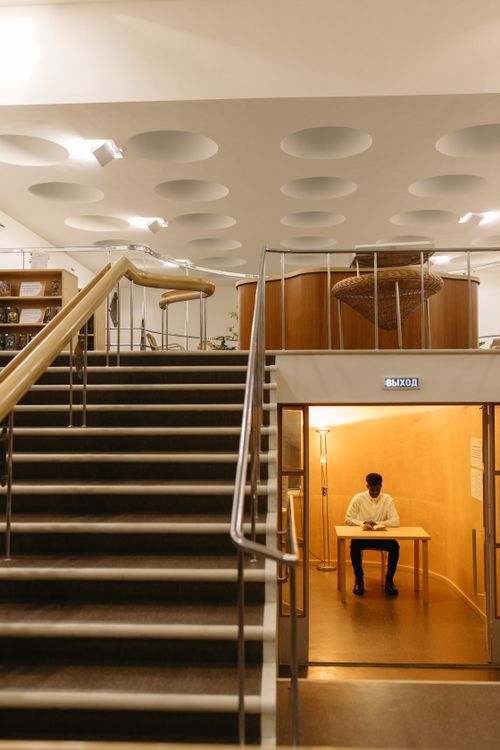 Free A student studying at a table in a modern library interior with unique ceiling design. Stock Photo