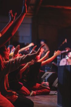 Energetic crowd emotionally engaged, raising hands during a live music concert indoors.