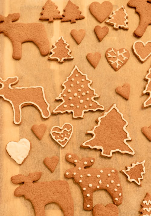 Top view composition of delicious sweet gingerbread cookies in shapes of Christmas tree and deer arranged on wooden table