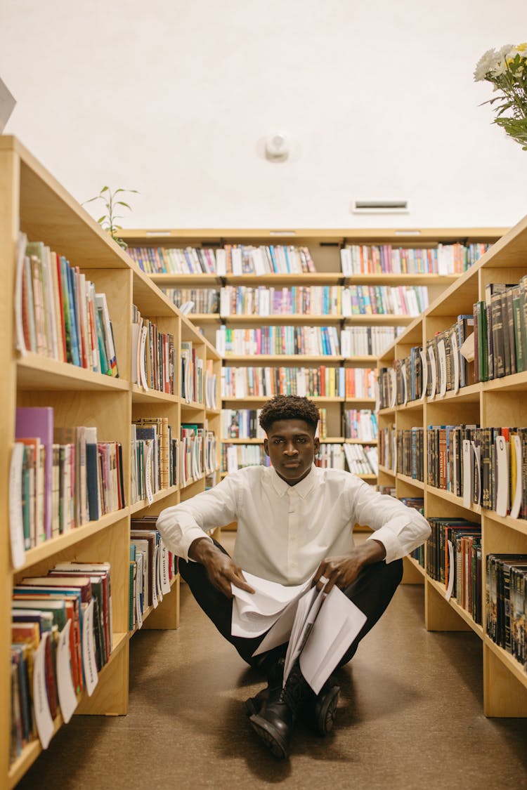 Man Sitting On The Floor In Library