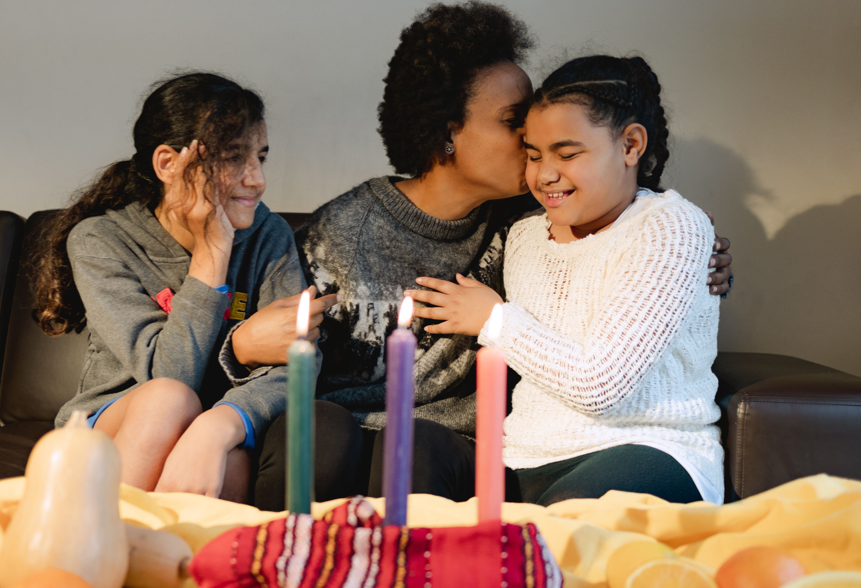 A joyful family celebrating Kwanzaa with colorful candles and smiles indoors.