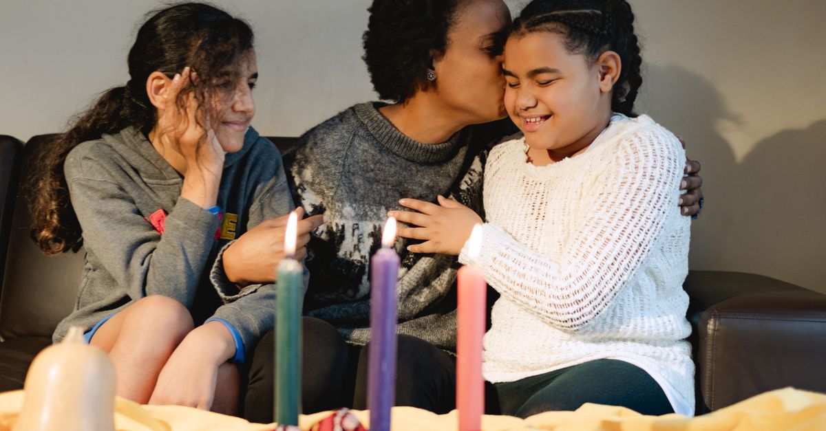 A joyful family celebrating Kwanzaa with colorful candles and smiles indoors.