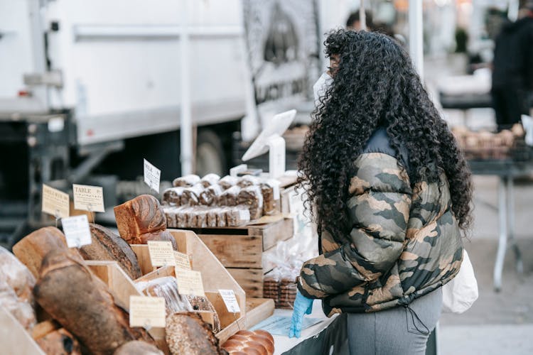 Ethnic Woman Buying Bread In Street Market