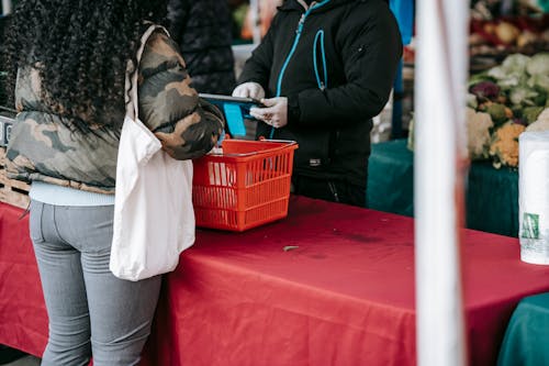 Customer and seller in protective gloves in food market