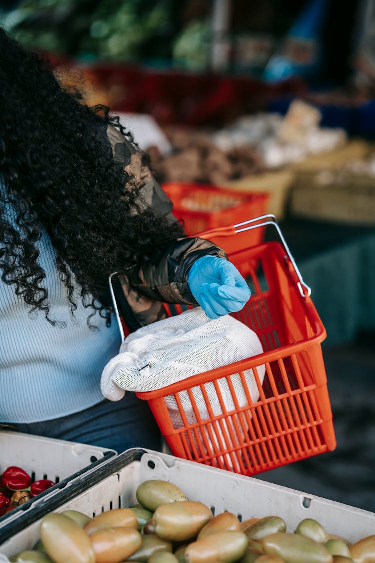 Crop Anonymous Woman In Gloves Standing With Basket In Supermarket