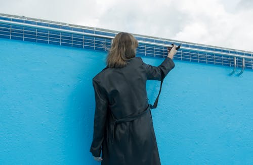 Kostenlos Frau Im Schwarzen Mantel, Der Nahe Blauer Wand Steht Stock-Foto