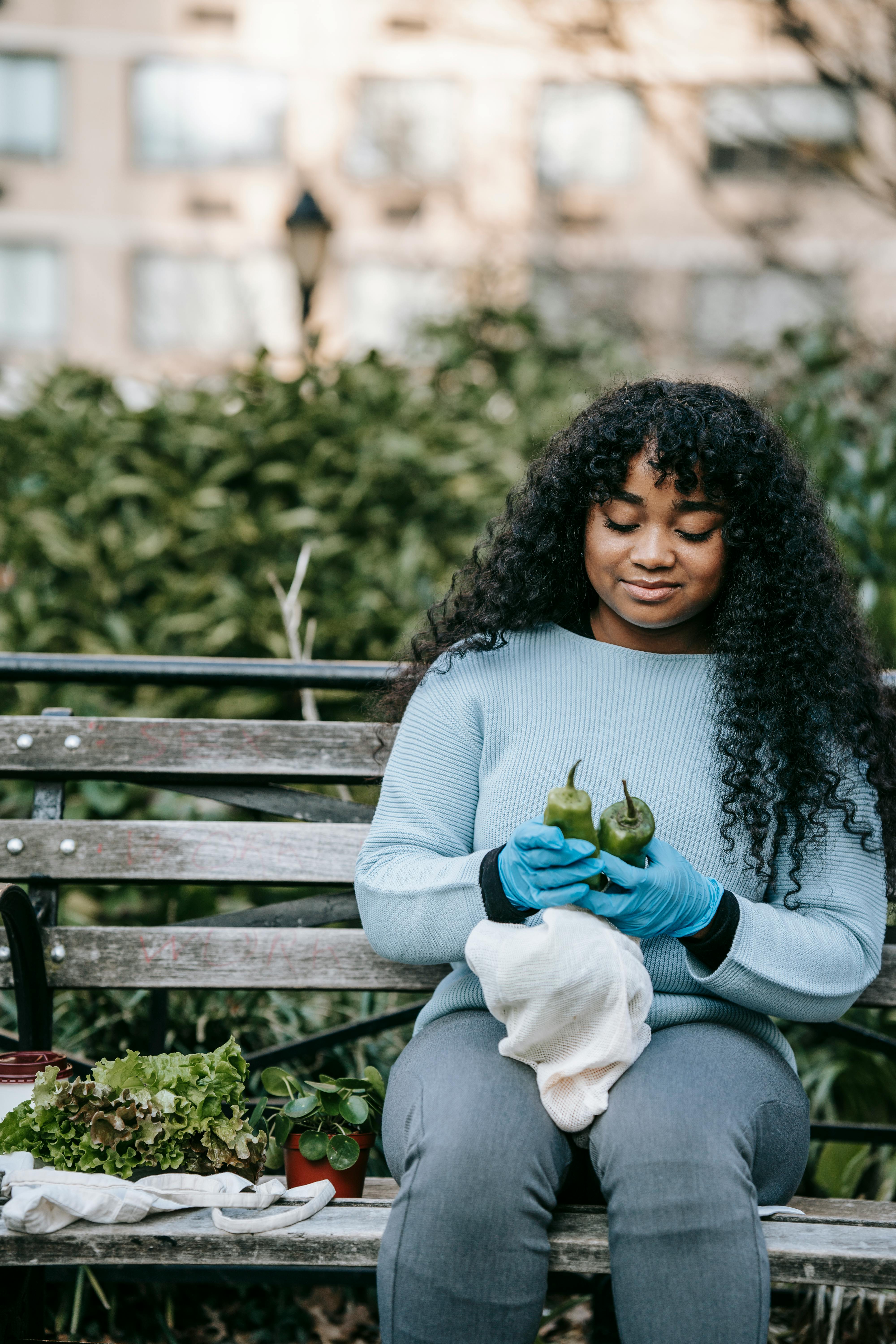 black lady in gloves with peppers and lettuce in street