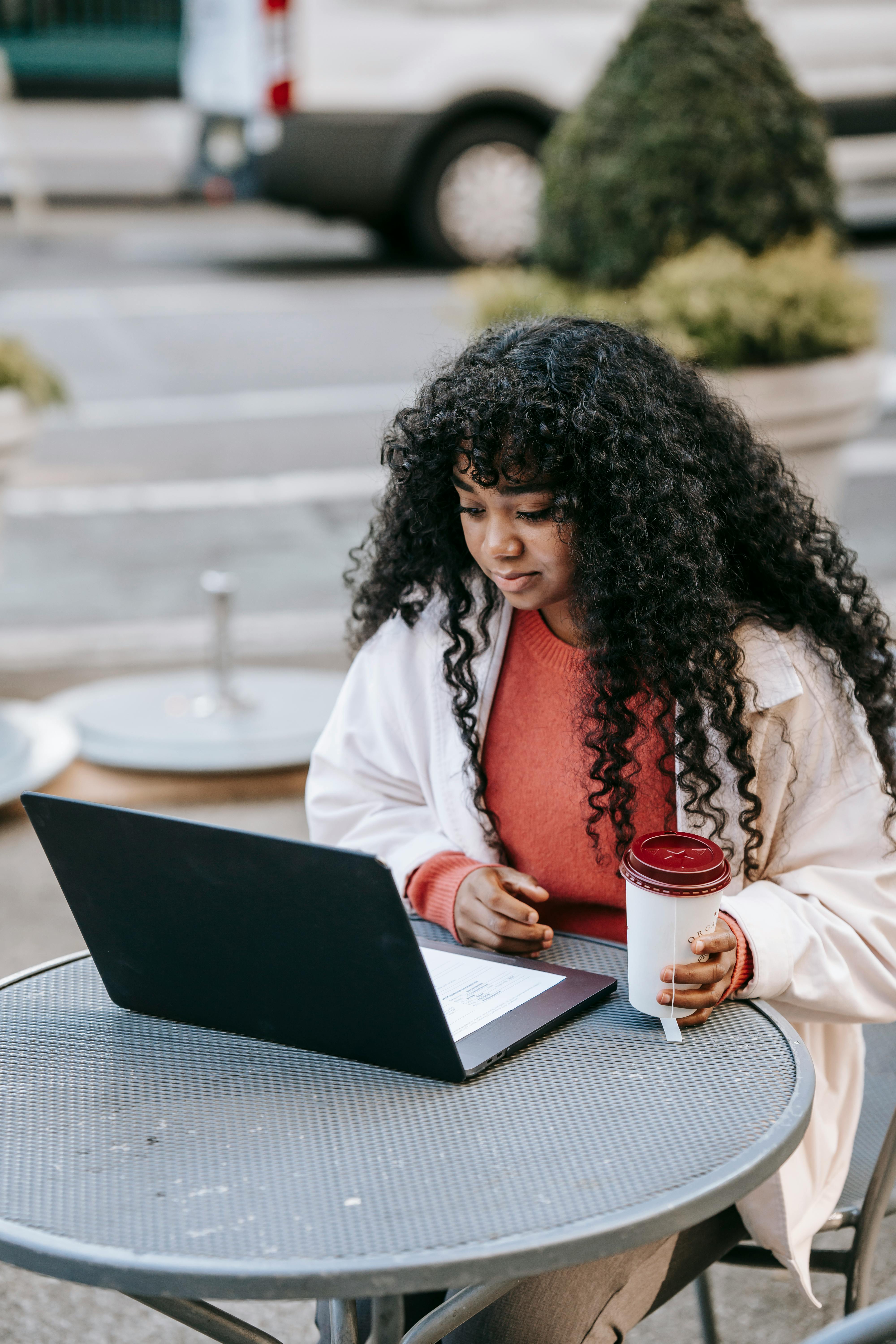 content black woman using laptop in outdoor cafeteria