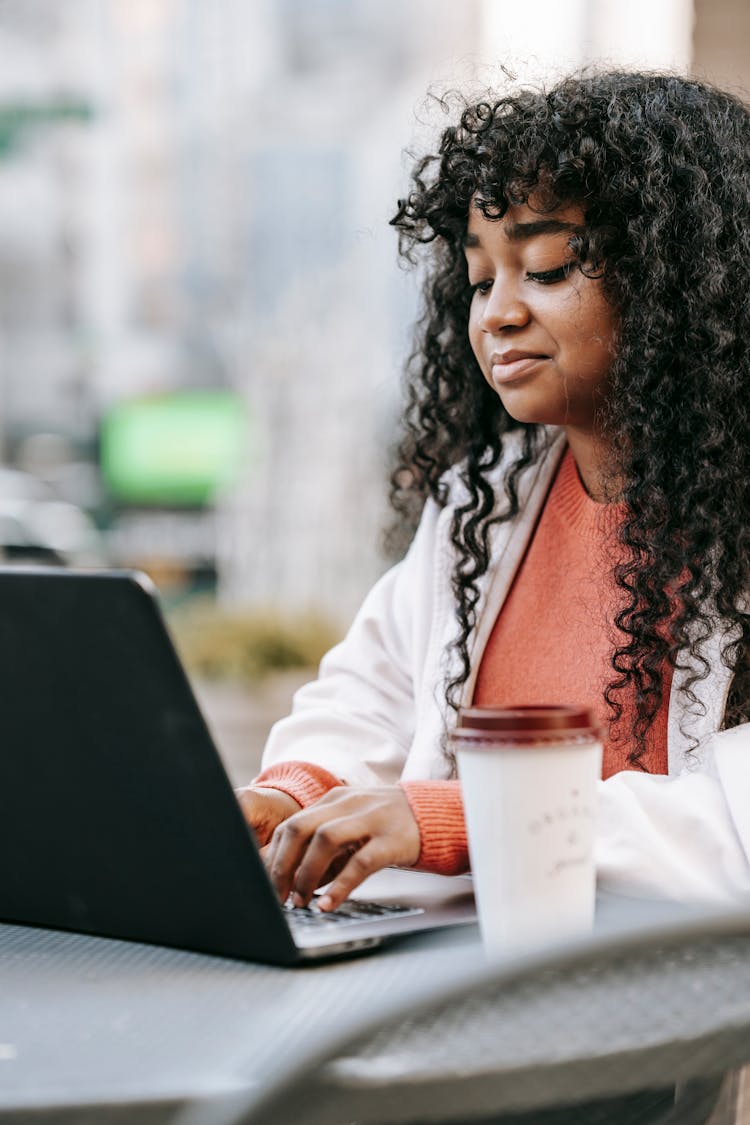 Content Black Woman Using Laptop In Street Coffee Shop