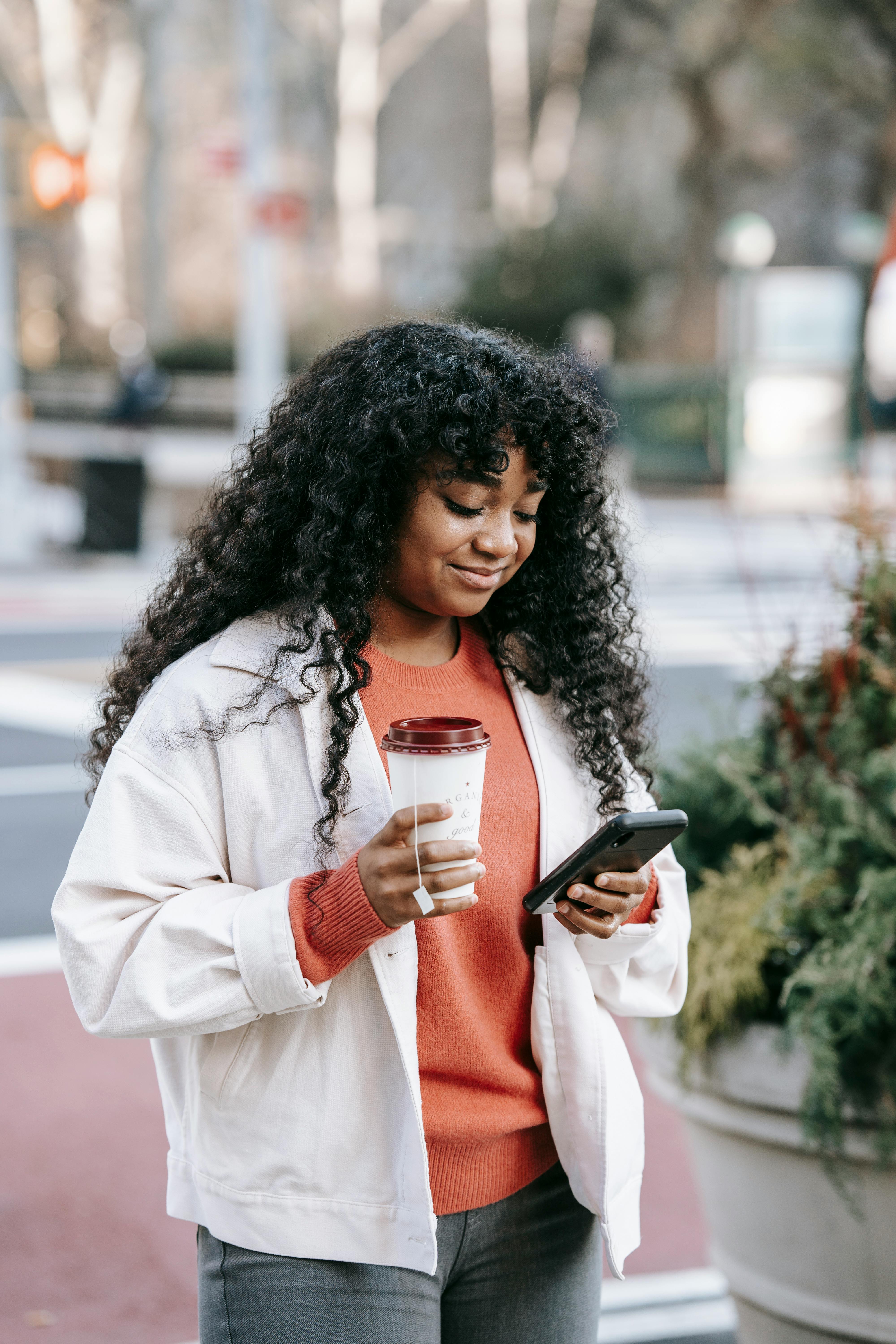 smiling black woman using smartphone on street