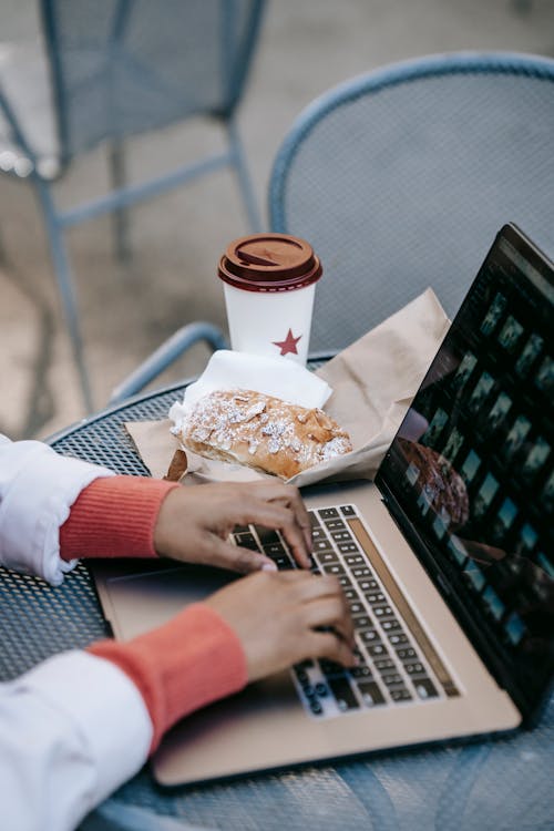 Free Crop faceless black woman working on laptop in outdoor cafe Stock Photo