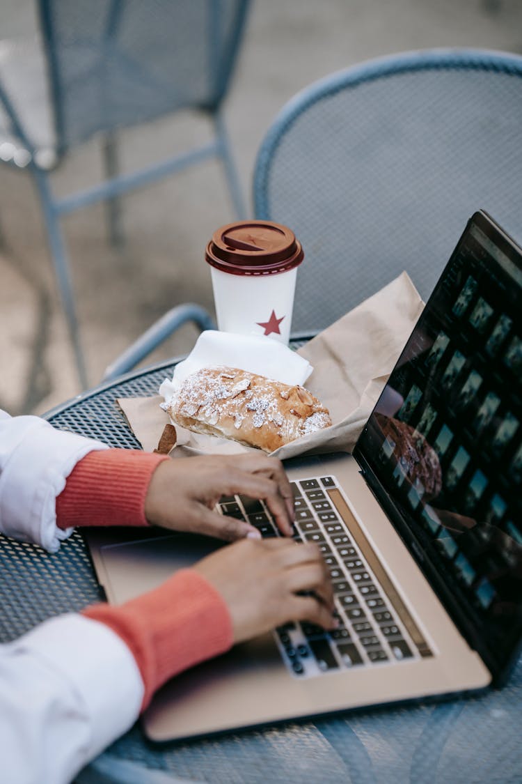 Crop Faceless Black Woman Working On Laptop In Outdoor Cafe