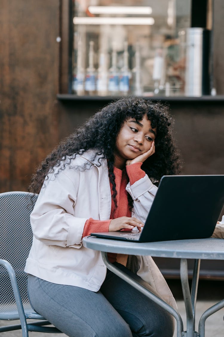 Black Woman Using Laptop In Outdoor Cafe