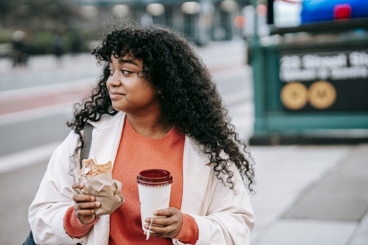 Content Black Woman With Takeaway Coffee And Sandwich On Street