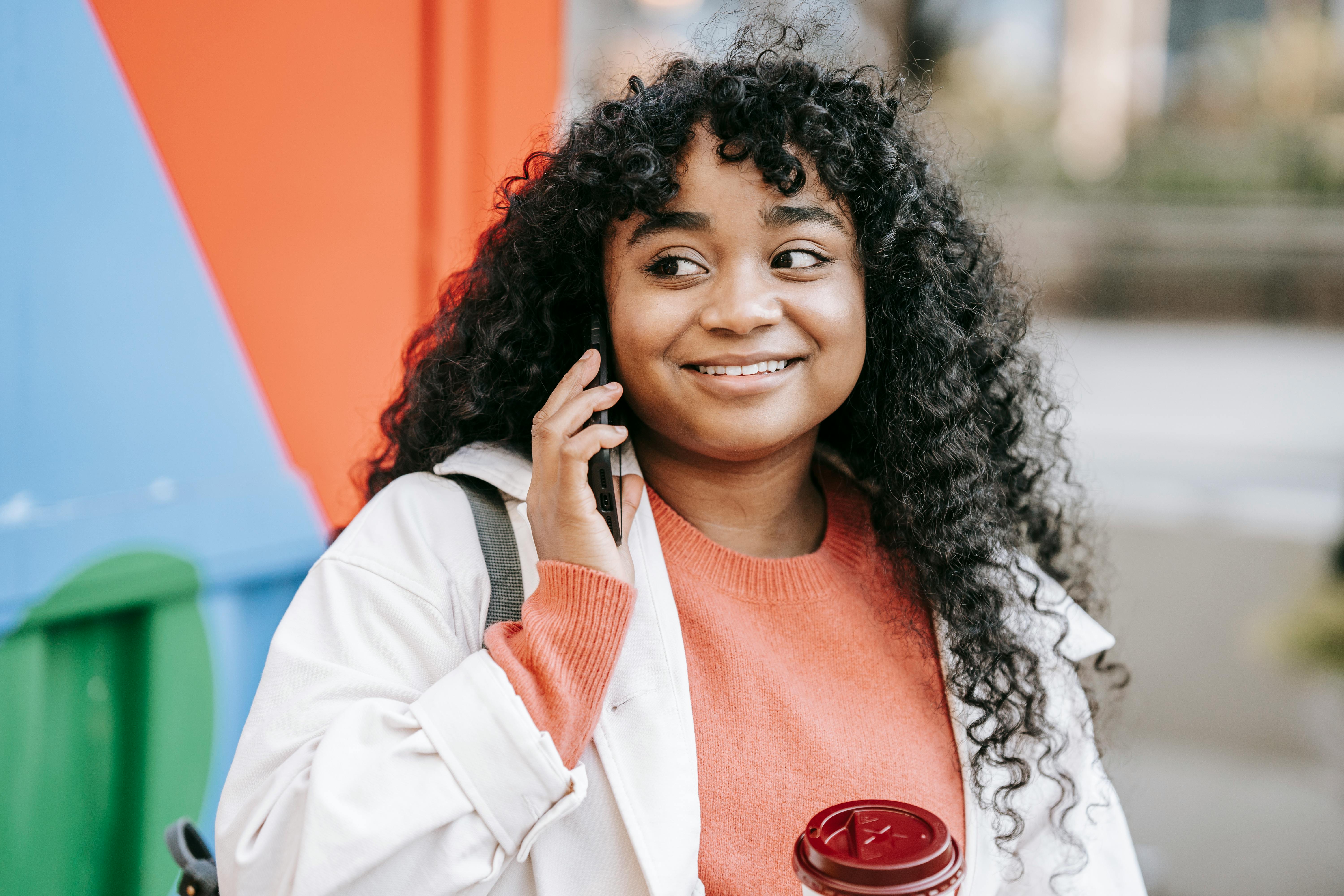 smiling black woman talking on smartphone on street