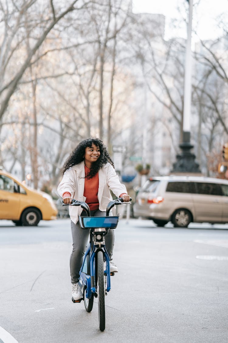 Joyful Black Woman Riding Bicycle On Street