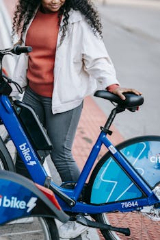 Woman standing next to a city rental bike in an urban setting during the day.