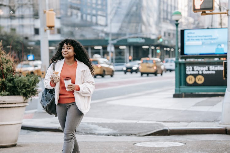 Black Woman With Takeaway Coffee And Sandwich Walking On Street