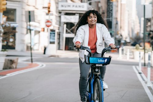 Free Content African American female in casual wear riding bicycle on modern city street in daylight Stock Photo