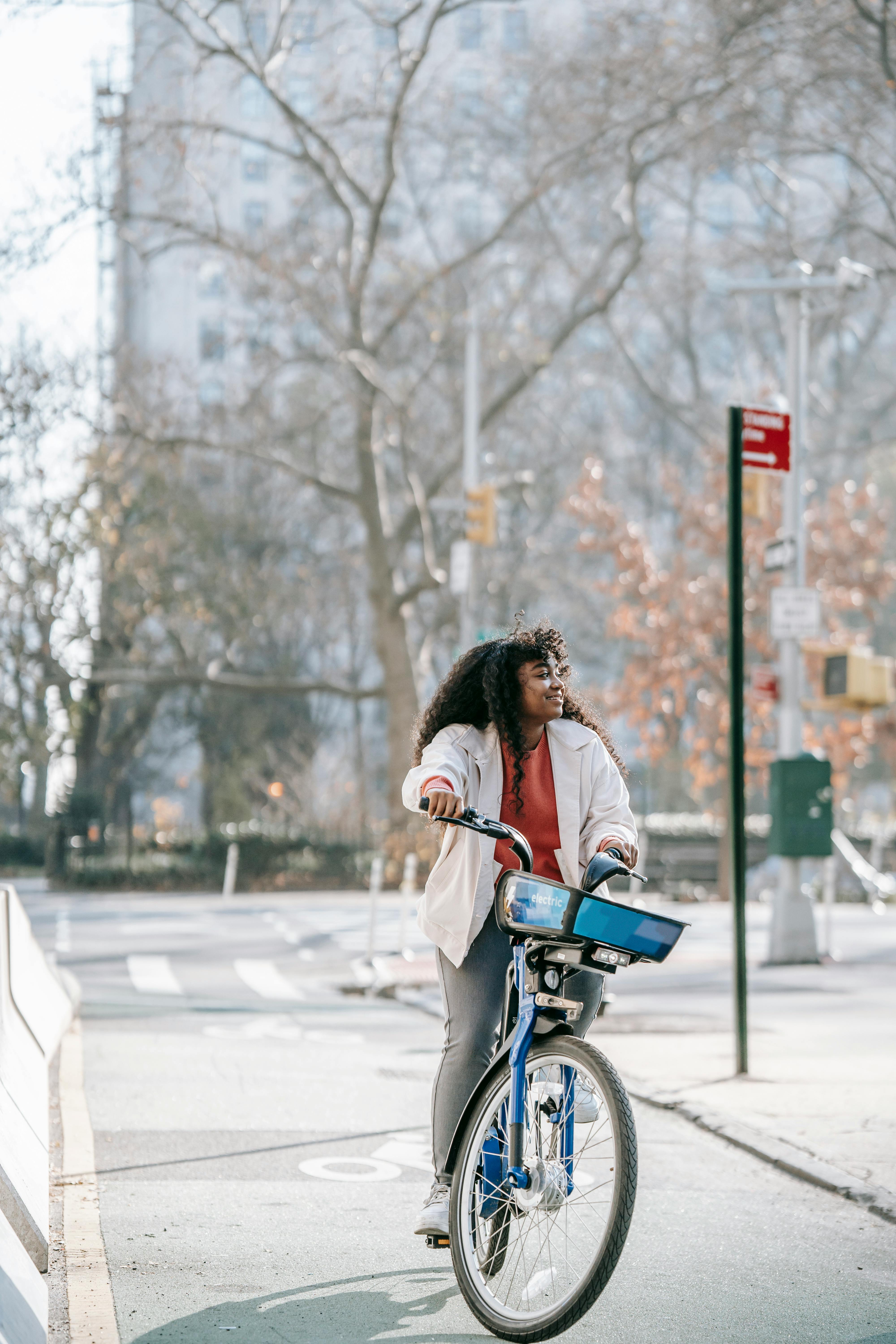 happy black woman riding bicycle on spring city street