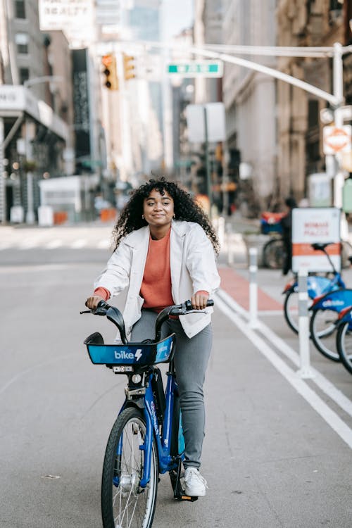 Free Positive African American female riding bike in city street Stock Photo