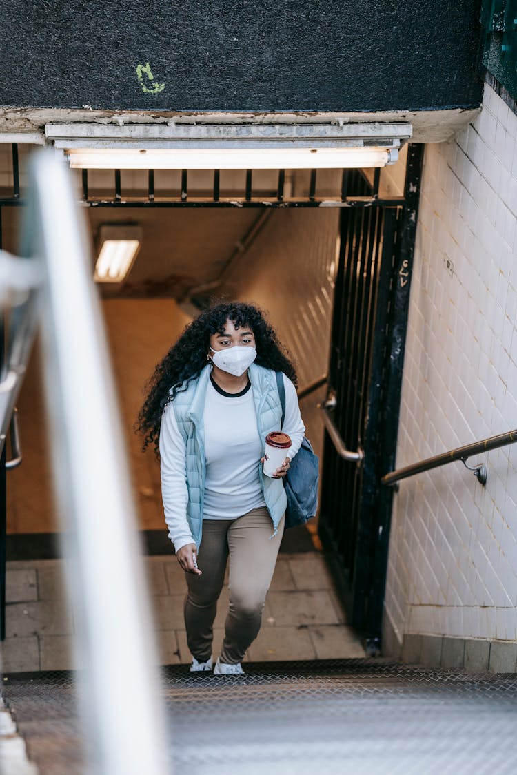 Black Woman In Mask Going Upstairs On Underground Passage