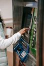 Crop anonymous African American female with takeaway coffee wearing casual outfit pressing soft buttons on ticket machine in underground station