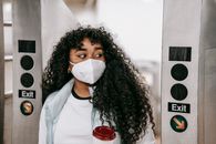 Black woman in mask passing through underground turnstile