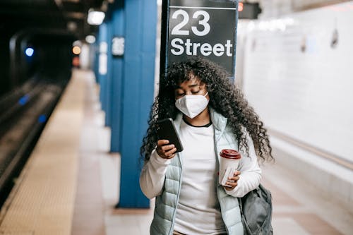 Focused black woman using smartphone on metro platform