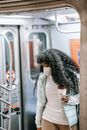 Calm African American female wearing casual outfit and face mask carrying coffee to go and exiting underground train