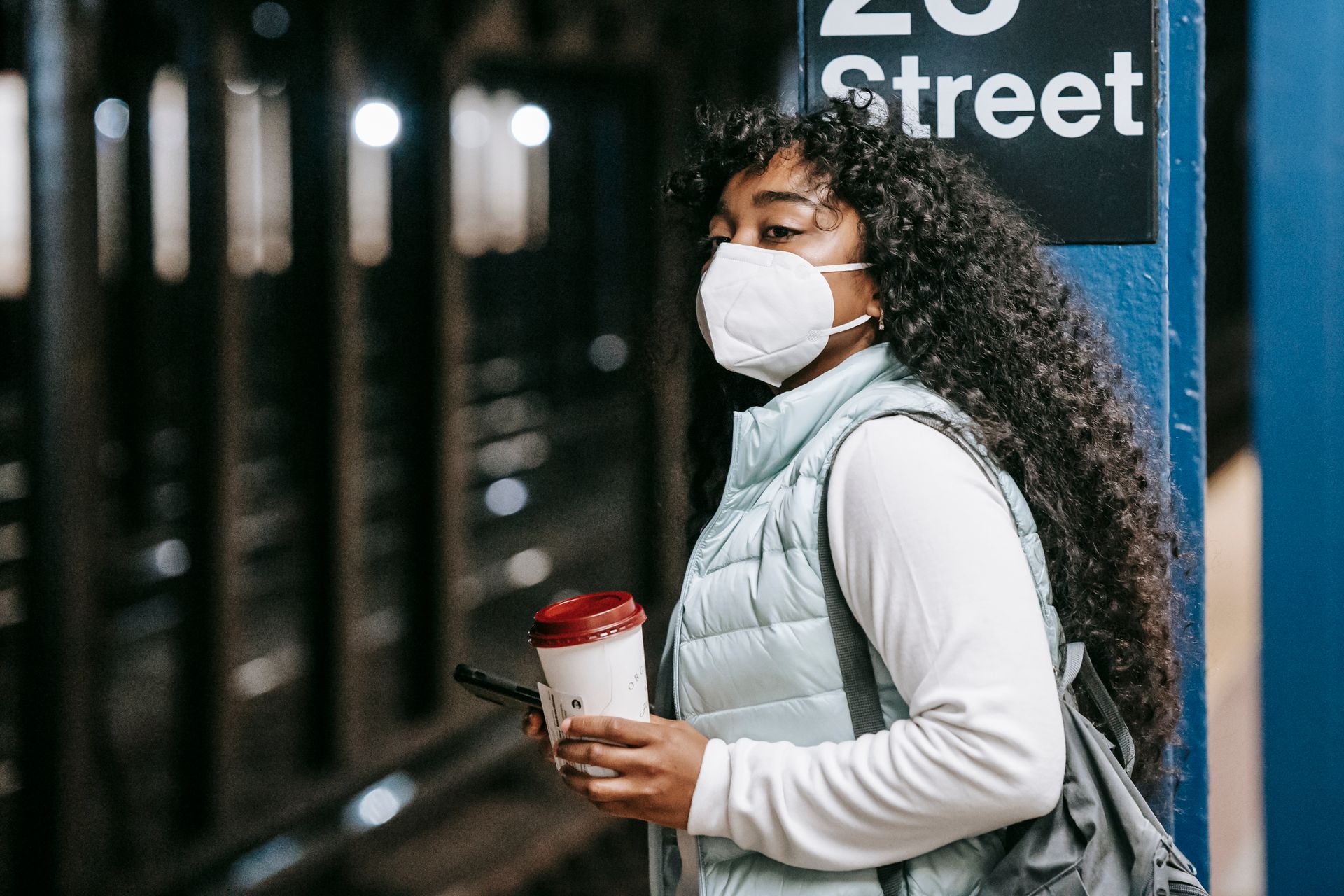 Black woman in respirator waiting for train in subway