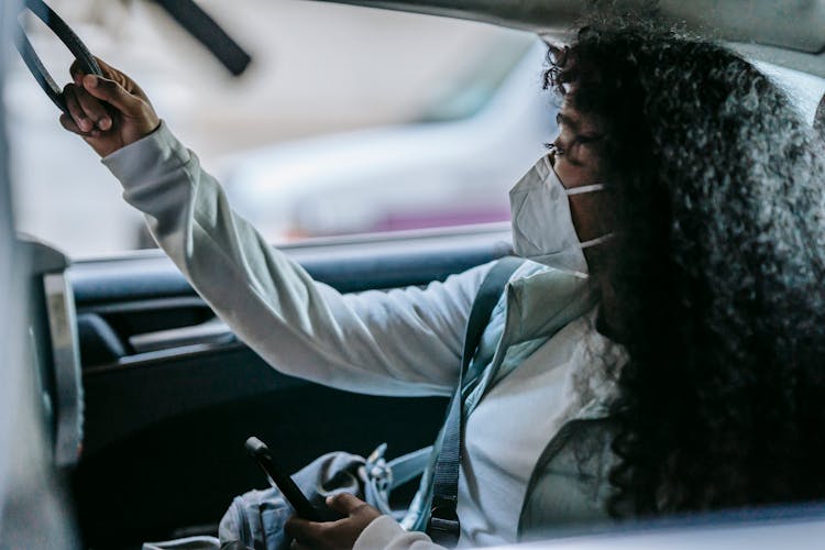 Unrecognizable Black Woman Messaging On Smartphone And Looking Through Car Window